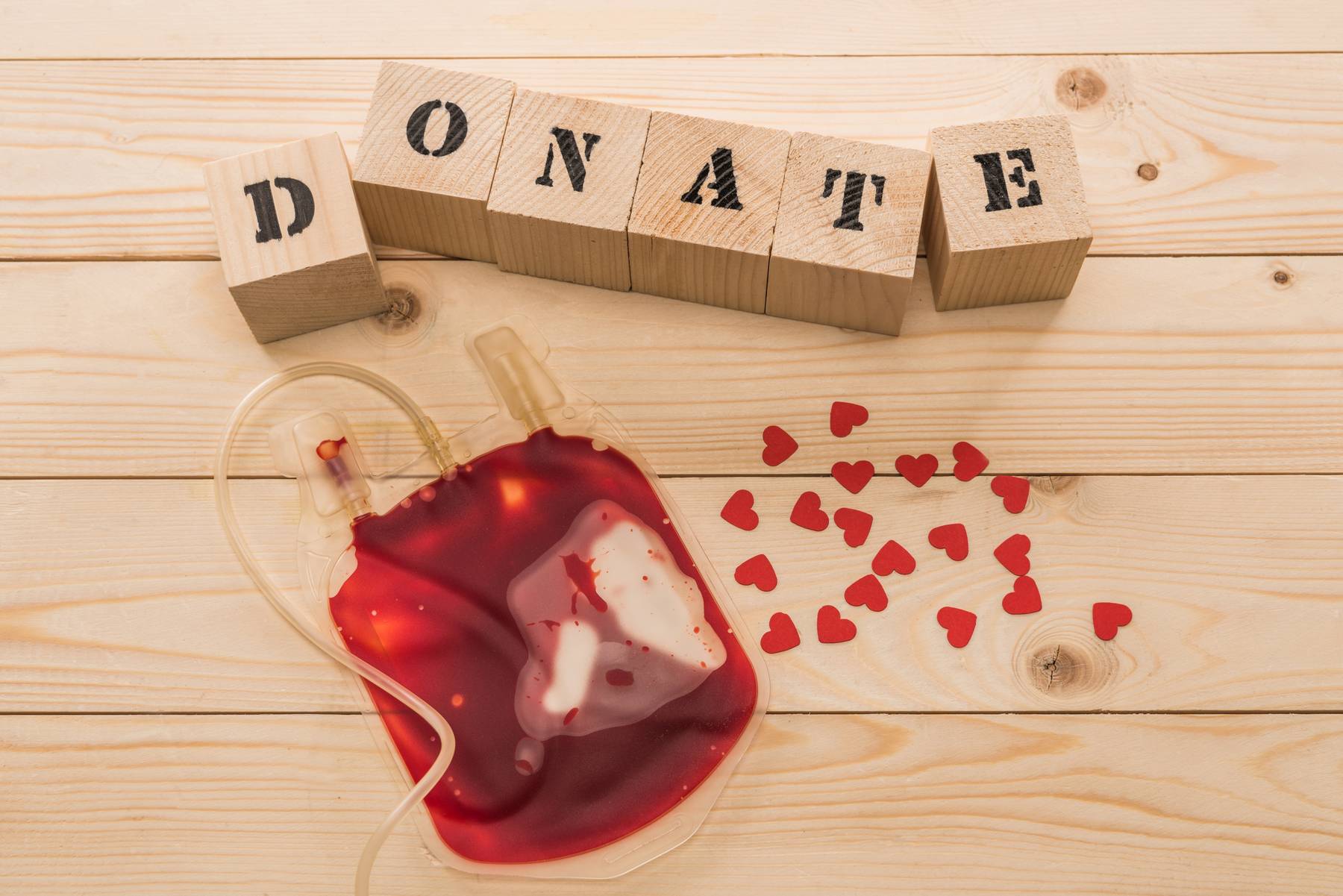 Top view of blood bag and wooden cubes with word donate, donation concept